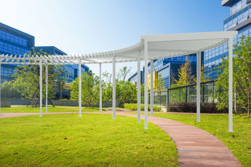 Commericial sun shade structure installed over a curving pathway in a downtown city park.