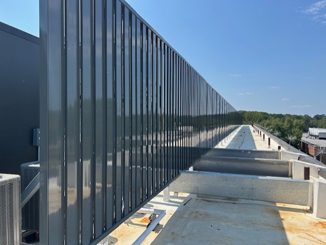 Gray rooftop screen with vertical planks and diagonal supports protecting an A/C unit.