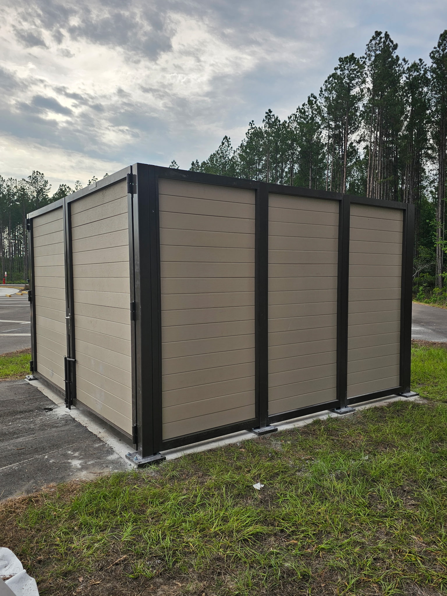 A dumpster enclosure made of horizontal planks, with trees in the background.